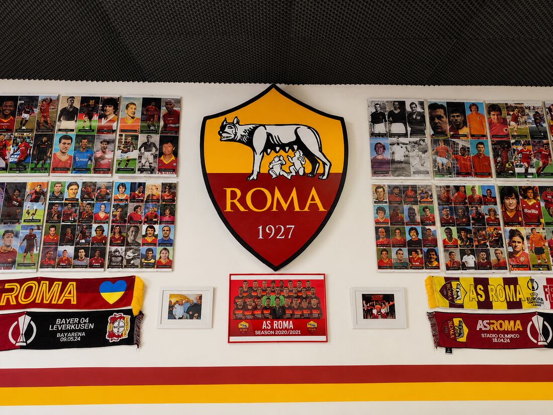 Parete della sede con lo stemma della Roma e le figurine dei giocatori